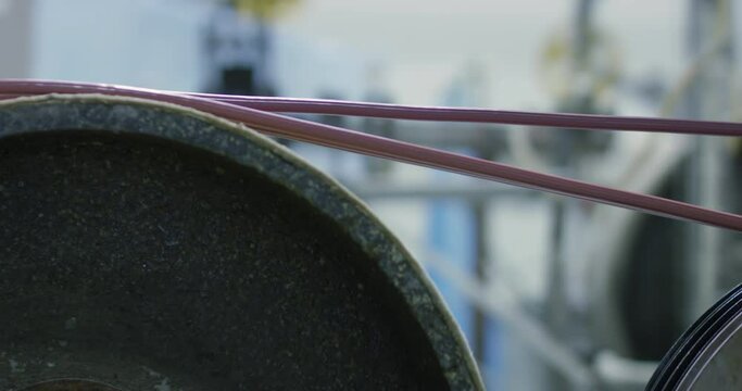 Stretching two copper wires along a metal drum. Work in the workshop for the manufacture of electrical wires. Shooting at close range.