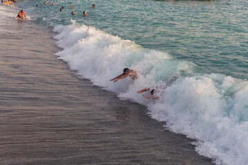 Turkiye, 2.09.2021: People swim in the sea and dive after the wave. People rejoice in the waves. Holidays in Turkey.