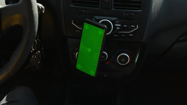 Woman sitting in car and attach her phone with vertical green screen.