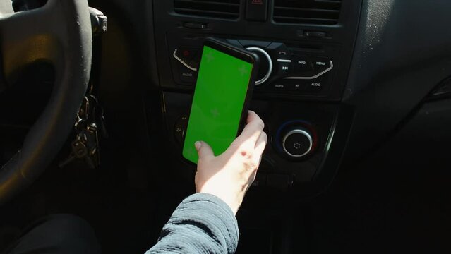 Woman sitting in car and using her phone with vertical green screen