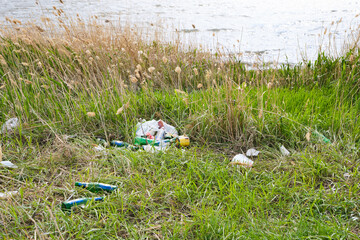 Polluted riverbank with discarded garbage, pollution ecology and environment.