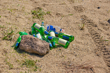 Discarded glass beer bottles sandy beach.