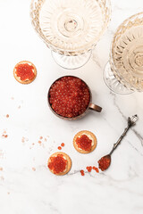 Elegant glass of champagne with red caviar on golden spoon and metal container of caviar, Gourmet food close up, appetizer, selective focus, place for text