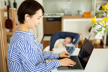 赤ちゃんをあやしながら仕事をする母親