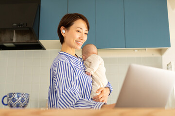 赤ちゃんをあやしながら仕事をする母親