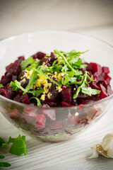 Salad with boiled beets, fried eggplants, herbs and arugula in a plate