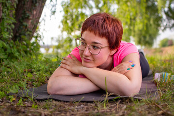 Naklejka na ściany i meble Beautiful young woman thinking and dreaming away while lying on the floor after working out on warm summer day