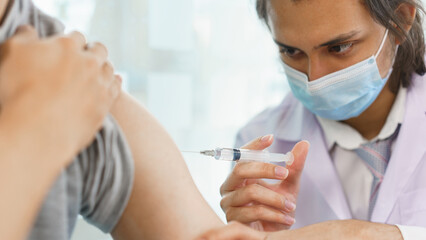 Vaccination concept, Male doctor in face mask injecting vaccine against covid-19 for male patient