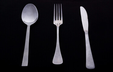 Silver old fork, spoon and knife on minimalistic black background