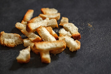 Crackers, dried baked bread light loaf, bunch of broken on dark background, selective focus.