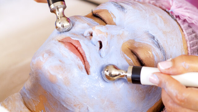 Woman in a spa salon on cosmetic procedures for facial care. Beautician makes medical procedures using a medical equipment. Cosmetologist making a woman a therapeutic procedure on a face.