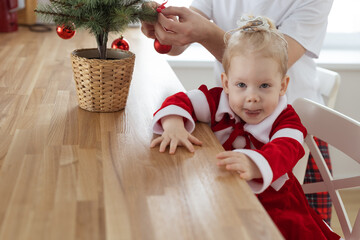 Child with cochlear implant hearing aid having fun with father and small christmas tree - diversity...