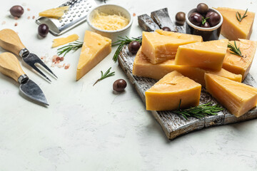 Parmesan cheese on a wooden board, Hard cheese, rosemary and cheese knife on a light background. place for text, top view