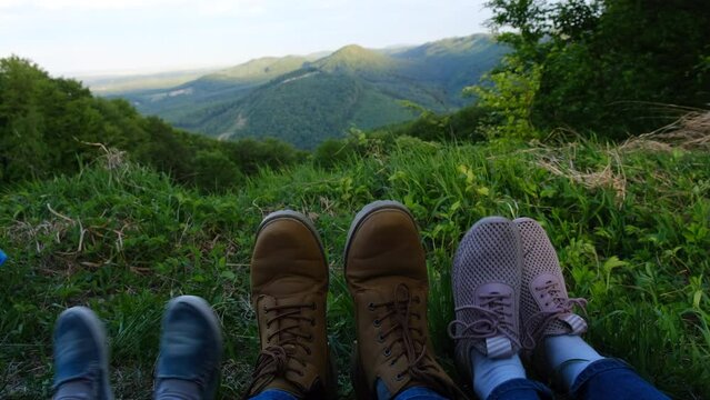 Close-up feets of resting father, mother and daughter child with beautiful mountain landscape on background. Hiker family enjoying vacation travel adventure Carpathians mountains. Wanderlust concept