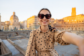 Happy woman taking selfie photo on the background of Roman forum. Style caucasian woman in dress and shawl in hair having fun traveling italian landmarks