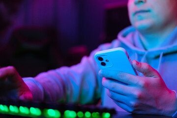 Man with a phone in hand in neon lighted interior. Toned like cinema effects in purple-blue....