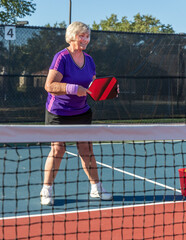 Senior pickleball player at the net demonstrating good position on the court