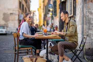 Man and woman eating italian pasta and drinking wine at restaurant on the street in Rome. Concept...
