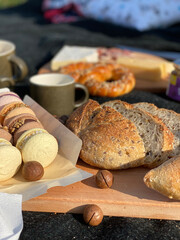 Macaroons, fruits, bread on a blanket. Picnic in nature at sunset.