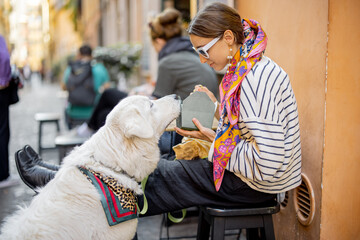 Woman cares her dog while eating pasta at outdoors cafe in Rome city. Concept of italian lifestyle,...