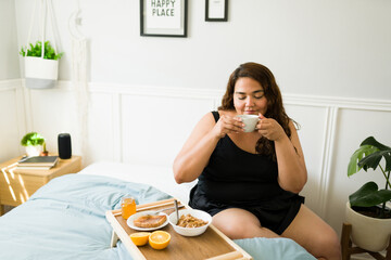 Obese woman relaxing with coffee in the bedroom