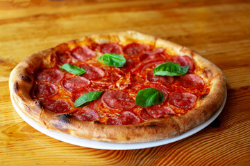 Delicious salami pizza with basil and spices on table