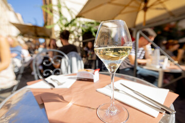 Glass of white wine on a restaurant table outdoors, close-up
