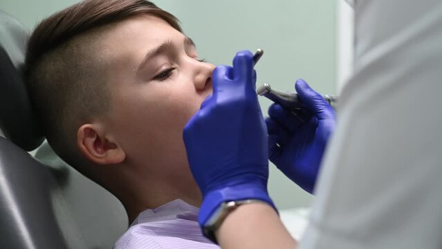 The dentist cleans the boy's teeth with a special device