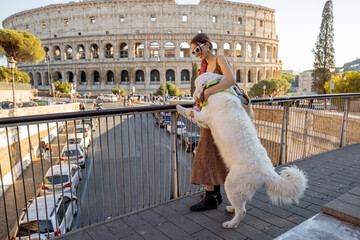 Woman playing with dog on the street near Coliseum in Rome. Street view with the most popular...