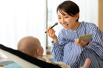 化粧をしながら赤ちゃんをあやす母親