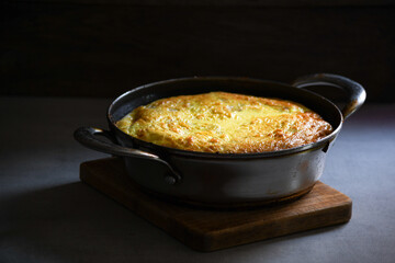 Rustic omelet with potatoes in a metal pan on the kitchen table.
