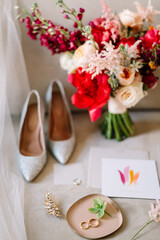 stylish details of the bride's morning, a bright bouquet and shoes, as well as invitation cards and wedding rings

