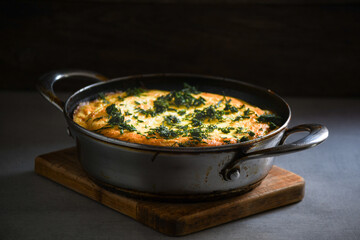 Rustic omelet with potatoes and herbs in a metal pan on the kitchen table.