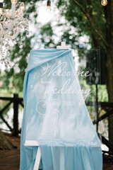 Glass board with welcome sign on it decorated with blue  cloth. Wedding. Reception.