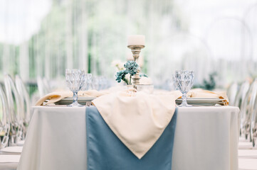 Outdoor banquet and modern design for wedding ceremony in summer. Linen tablecloth, candles, flowers and accessories, glasses and plates on table for guests with chairs, flat lay, nobody