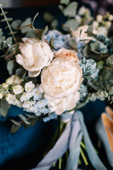 Bridal bouquet. Bridal shoes. Rings. The bride's bouquet. Beautiful bouquet of white, blue, pink flowers and greenery, decorated with long silk ribbon lies on a blue chair
