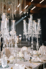 Dinner table rich decorated by candles and flowers. Luxury Wedding decor. Gorgeous concept