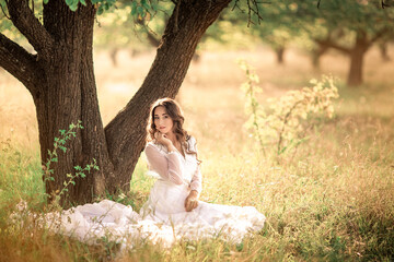 Girl with long hair in an old dress in the garden