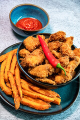 Fried, spicy chicken nuggets served with sweet potato fries. Decorated with chilli peppers - obrazy, fototapety, plakaty