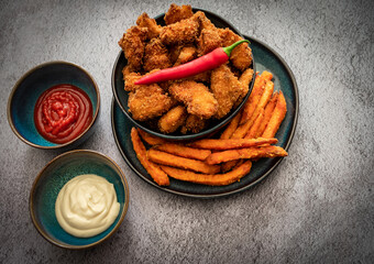 Fried, spicy chicken nuggets served with sweet potato fries. Decorated with chilli peppers