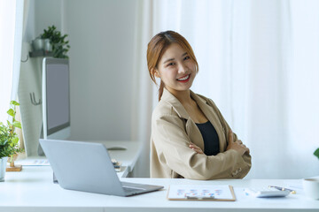 Confident successful Asian business woman sitting smiling looking at camera in office.