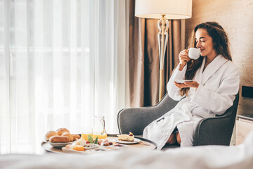 Woman eating breakfast in the hotel room. Room service breakfast in hotel room.