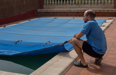 Destapando la piscina al inicio del verano dos hombres, agua sucia y verde, necesidad de...