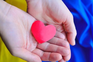 Red heart in hands, Yellow and blue Ukrainian flag, national symbols 