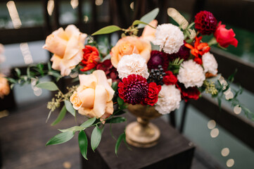 Beautiful flower composition with autumn orange and red flowers and berries. Autumn bouquet in vintage vase on a wooden table 