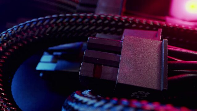 Close-up power supply connection cables to computer motherboard wrapped in mesh material. High quality 4k footage