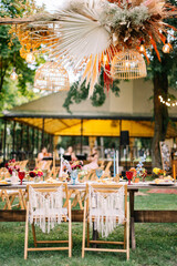 Fototapeta na wymiar Wedding boho arch decorated with flowers for ceremony against the forrest landscape. wedding ceremony in boho style. Outdoor party