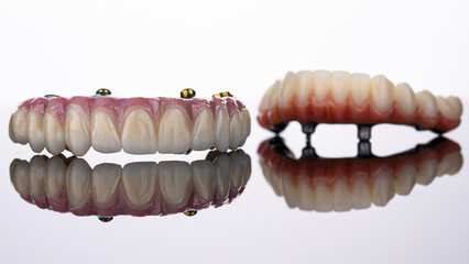 two dental prostheses of the upper and lower jaws on a white background with reflection