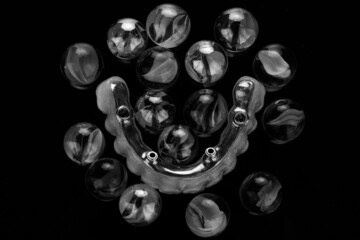 creative dental photo on dental prosthesis and glass beads, top view in black and white style