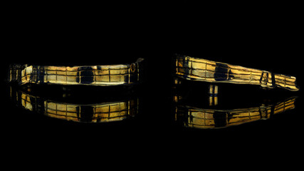 two dental bars of gold color of the upper and lower dentures on black glass